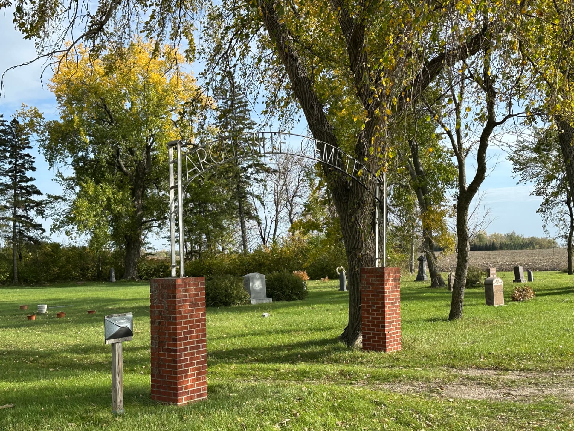 The entrance arch at Argusville Cemetery, surrounded by mature trees